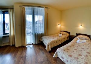 バンスコにあるMountain Romance Family Hotelのベッド2台と大きな窓が備わるホテルルームです。