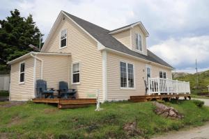a white house with two chairs on a porch at Seaside Serendipity Cottage in Herring Neck