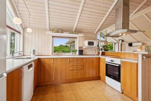 une grande cuisine avec des placards en bois et une fenêtre dans l'établissement Beachside Holiday Home For The Whole Family, à Broager