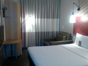 a hotel room with a bed and a chair and a bed and a couch at ibis Navegantes Itajai in Itajaí