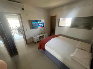 ein Schlafzimmer mit einem Bett und einem Flachbildfernseher in der Unterkunft Ap 2 quartos em frente ao Campim Dourado Shopping in Palmas