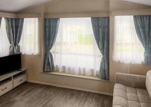 ein Wohnzimmer mit 2 Fenstern und einem TV in der Unterkunft Towervans Caravan Park in Mablethorpe