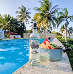 Una botella de vino junto a un frutero al lado de una piscina en Swim & Paint Art Retreat, en Las Piedras