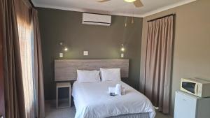 een slaapkamer met een bed met witte lakens en kussens bij Postmasburg Inn in Postmasburg