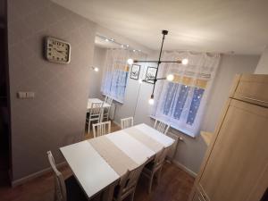 Dwa poziomy Wrocławska في بياويستوك: مطبخ وغرفة طعام مع طاولة وكراسي بيضاء +صورتان