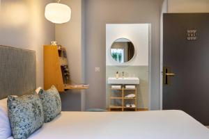 a bedroom with a bed and a sink and a mirror at Hôtel Eiffel Saint Charles in Paris