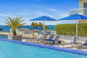 uma piscina com espreguiçadeiras e guarda-sóis em Harbor House em Oranjestad