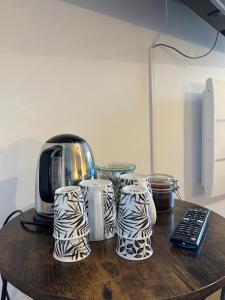 a table with three coffee cups and a toaster at Au Gray du temps suspendu in Pleslin-Trigavou