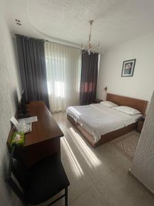 ein Hotelzimmer mit einem Bett und einem Schreibtisch und einem Schreibtisch in der Unterkunft Green Hotel in Almaty