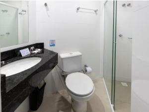 a bathroom with a toilet and a sink and a shower at Hotel Pitol in Balneário Camboriú