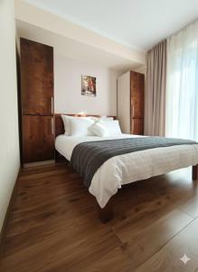 ein Schlafzimmer mit einem großen Bett mit Holzboden in der Unterkunft მგზავრები Mgzavreni IV აპარტამენტი Apartment 205 in Itʼkhvisi