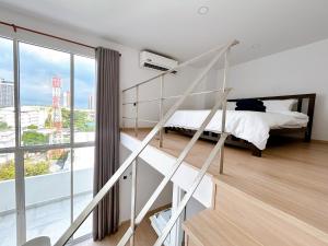 a bedroom with a bed and a large window at Komfort Duplex BTS Ratchayothin in Bangkok