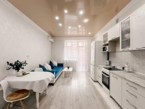 a white kitchen with a table and a blue couch at 2х комнатная квартира в ЖК Ирина in Pavlodar +12 photos