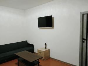 Una sala de estar con un sofá y un televisor en una pared. en cozy haven hostel, en Aghk'ilisa