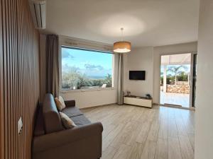 a living room with a couch and a large window at Villa Vitruvio - Giardino degli Allori Scopello in Castellammare del Golfo