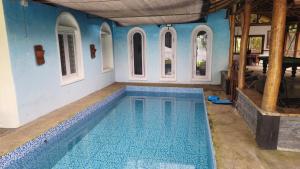 une grande piscine dans une maison aux murs bleus dans l'établissement Grace Backwater Villa Coorg, à Suntikoppa 75 autres photos
