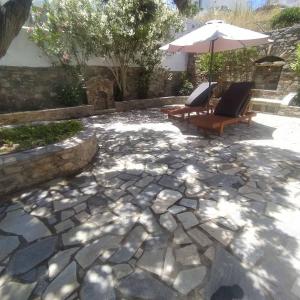un patio avec deux chaises et un parasol dans l'établissement Πέτρινη αυλή, Αρμενιστης Ικαρια, à Armenistis