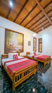 two beds in a room with a painting on the wall at Nirosha Guest House in Galle