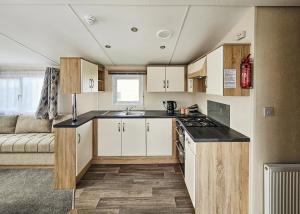 eine Küche mit weißen Schränken und einem Sofa in einem Zimmer in der Unterkunft Ty Gwyn Park in Abergele