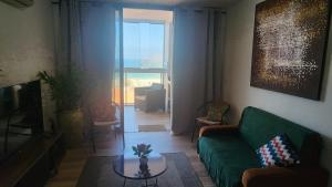 a living room with a green couch and a table at Piratininga - Niterói RJ in Niterói
