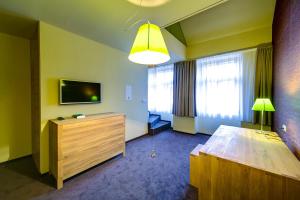 una habitación de hotel con televisión y cómoda de madera en Hotel Restaurant Darwin, en Praga