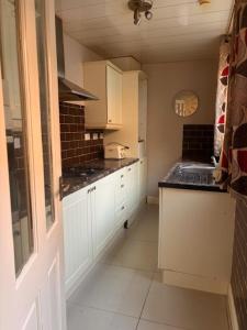 a kitchen with white cabinets and black counter tops at Croft Guest House in South Shields