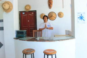 a woman standing in front of a table with stools at Malaka ocean homestay in Kuta Lombok