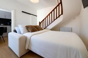 ein weißes Bett in einem Zimmer mit einer Treppe in der Unterkunft Le Nest in La Celle-sous-Gouzon