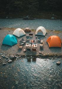 un groupe de tentes avec des tables et des chaises dans l'eau dans l'établissement Trail4WD Adventure Camp Malshej Hills, à Malshej Ghat