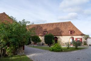 a large stone house with red windows and a driveway at Maison 2 in Souvigny