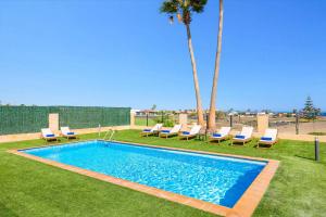 a swimming pool with lounge chairs and a palm tree at Villa Humaik by Villa Plus in Antigua