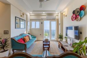 a living room with a blue couch and a tv at The Sky Penthouse - Mussoorie Rd Da Alohas Retreat in Dehradun