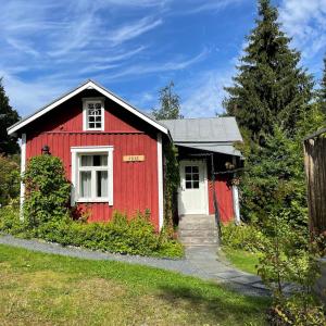 a red house with a white door in a yard at Torppa, puusauna ja ilmastointi in Lahti