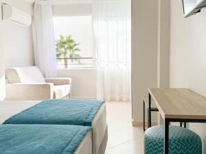 ein Schlafzimmer mit einem Bett, einem Schreibtisch und einem Tisch in der Unterkunft Hotel Atismar in Quarteira