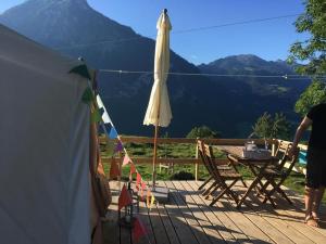 un patio avec un parasol, une table et des chaises dans l'établissement Zeltferien Into The Wäid Zelt Unter Der Esche, à Ennetmoos
