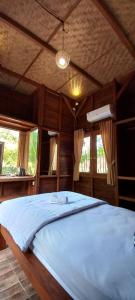 a large bed in a room with windows at Kubu Nadhi in Ketewel