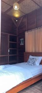 a bedroom with a bed with a wooden headboard at Kubu Nadhi in Ketewel