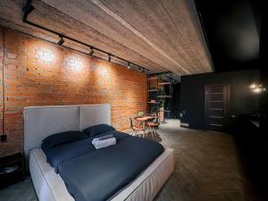 a bedroom with a bed and a brick wall at Люкс в стиле LOFT in Pavlodar +12 photos