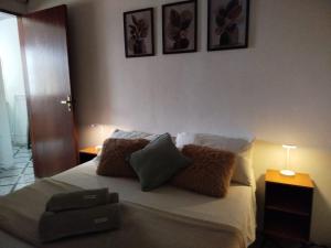 una camera da letto con un letto con cuscini e due tavoli di Sunset Flats - Flat de 2 quartos bem perto das praias e na rua Pituba 1 a Itacaré