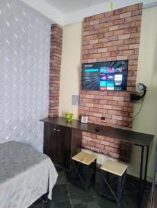 ein Schlafzimmer mit einem Fernseher an einer Ziegelwand in der Unterkunft Loft em rua de comércio em condomínio in Curitiba