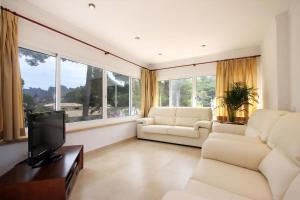 - un salon avec deux chaises et une télévision à écran plat dans l'établissement Villa Medina, à Cala Sant Vicenç