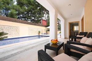 - un salon avec des chaises et une piscine dans l'établissement Villa Medina, à Cala Sant Vicenç