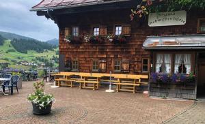 Un edificio de madera con bancos y mesas delante. en Selbstversorgerhütte N 15 Kleinwalsertal, en Hirschegg