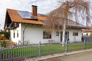 ein weißes Haus mit einem Sonnendach und einem Zaun in der Unterkunft Ferienwohnung Tannhausen in Aulendorf