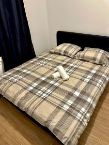 ein Bett mit einer karierten Bettdecke und einem Stofftier darauf in der Unterkunft Réf A Chambre à 6 min de Disneyland Paris in Chessy