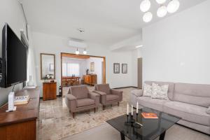 a living room with a couch and chairs and a tv at Casa Centrale by Nomads in Paphos City