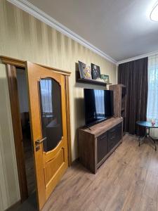 ein Wohnzimmer mit einem TV und einer Holztür in der Unterkunft Унікальні двокімнатні апартаменти класу ЛЮКС in Solotschyn