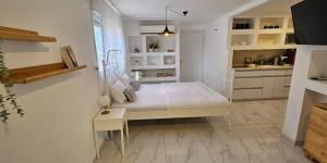 a white bedroom with a bed and a kitchen at נווה שחר- צימר משפחתי מקסים עם ג'קוזי פרטי ובריכה ליד הכנרת in Poriyya Illit