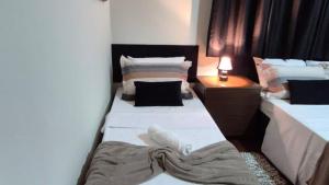 2 Einzelbetten in einem Zimmer mit einer Lampe in der Unterkunft Casa ampla perto do Aeroporto de Viracopos in Viracopos