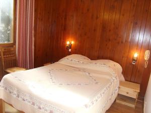 a bedroom with a white bed with wooden walls at Stellina in Lanslevillard
